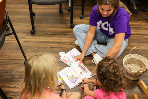 Student reading books to children