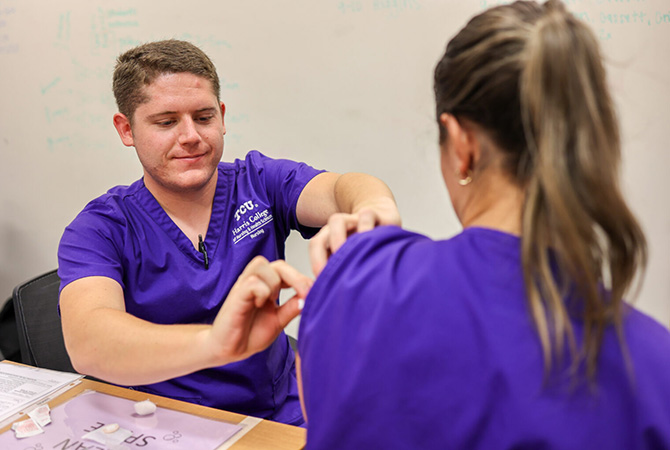 TCU Nursing senior practices administering the flu vaccine on another student in preparation for the upcoming flu clinic event.